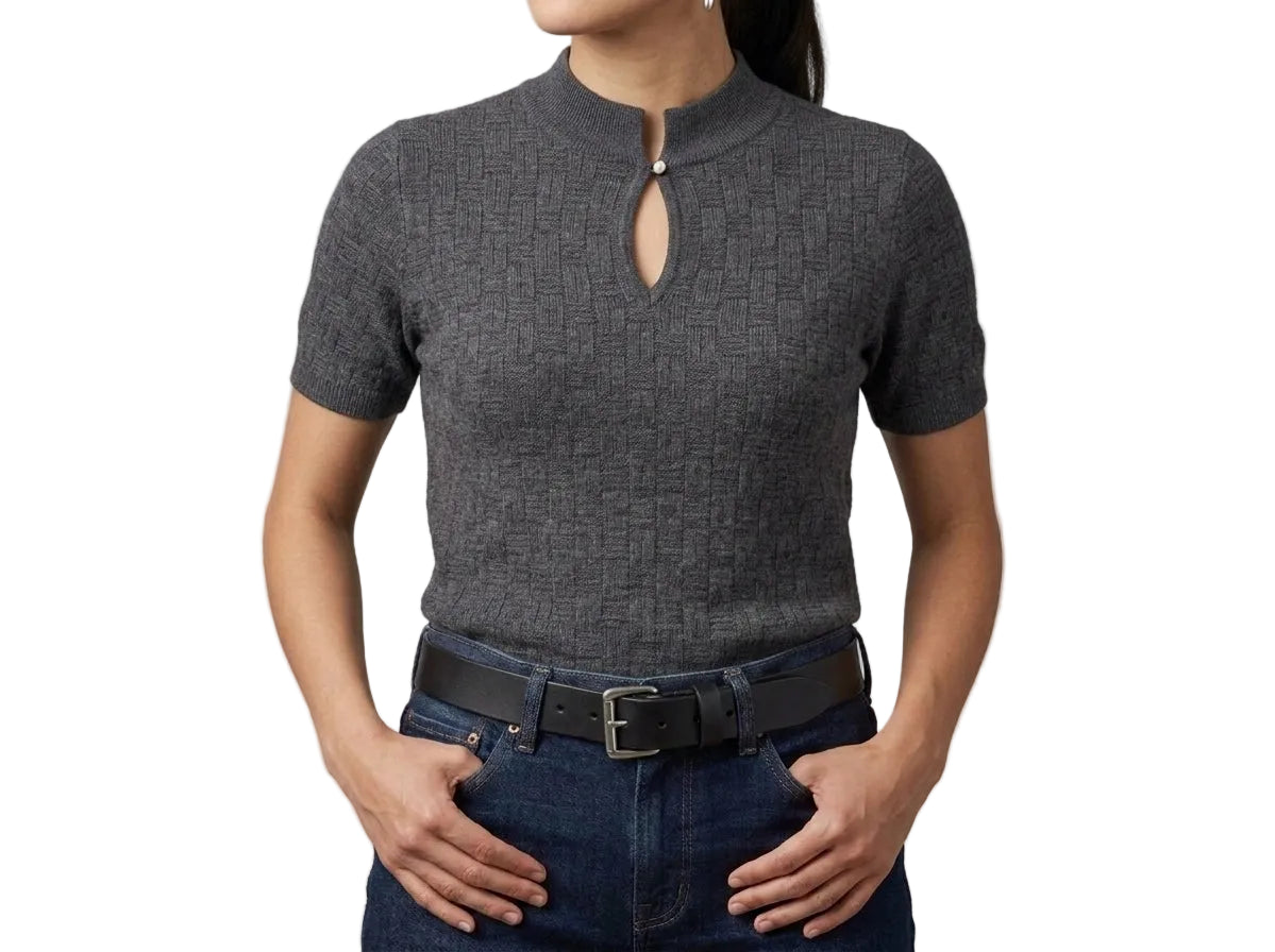 A woman wearing a dark gray textured short-sleeve knit top with a mock neck and keyhole cutout, paired with dark blue jeans and a black belt, against a solid gray studio background.